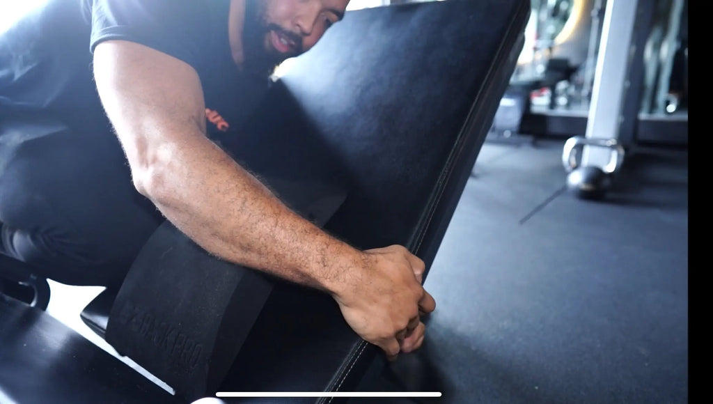 rainer securing the EZBack Pro Level 1 strap to a leg press machine, setting up for improved spinal support during lower body training.