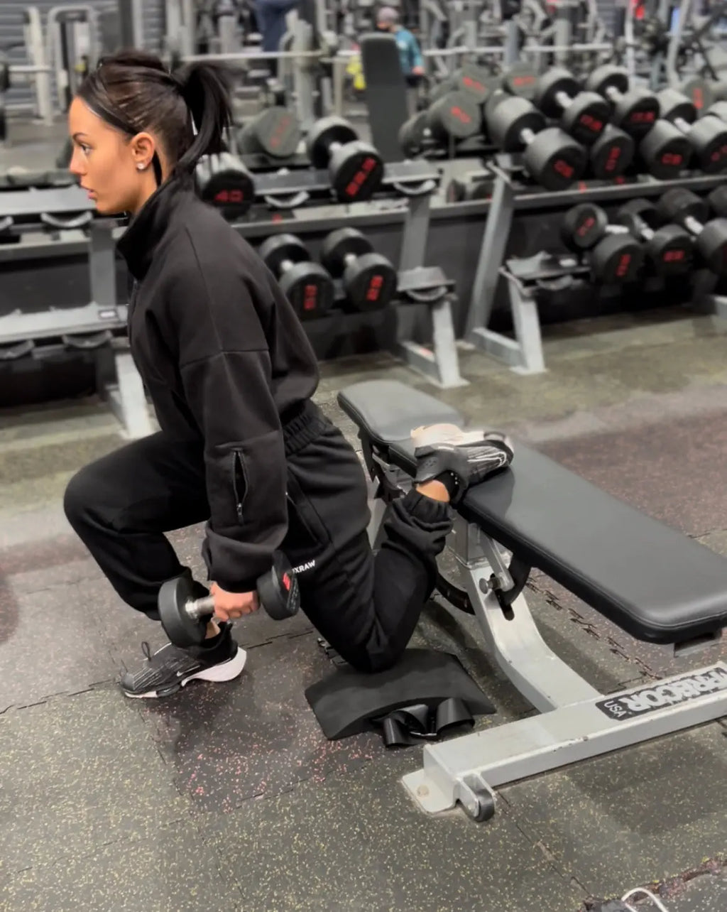 Cherneka 'Sug Kneez' Johnson performing a Bulgarian split squat using the EZBack Pro Level 1 strap as rear foot support for improved comfort and positioning.
