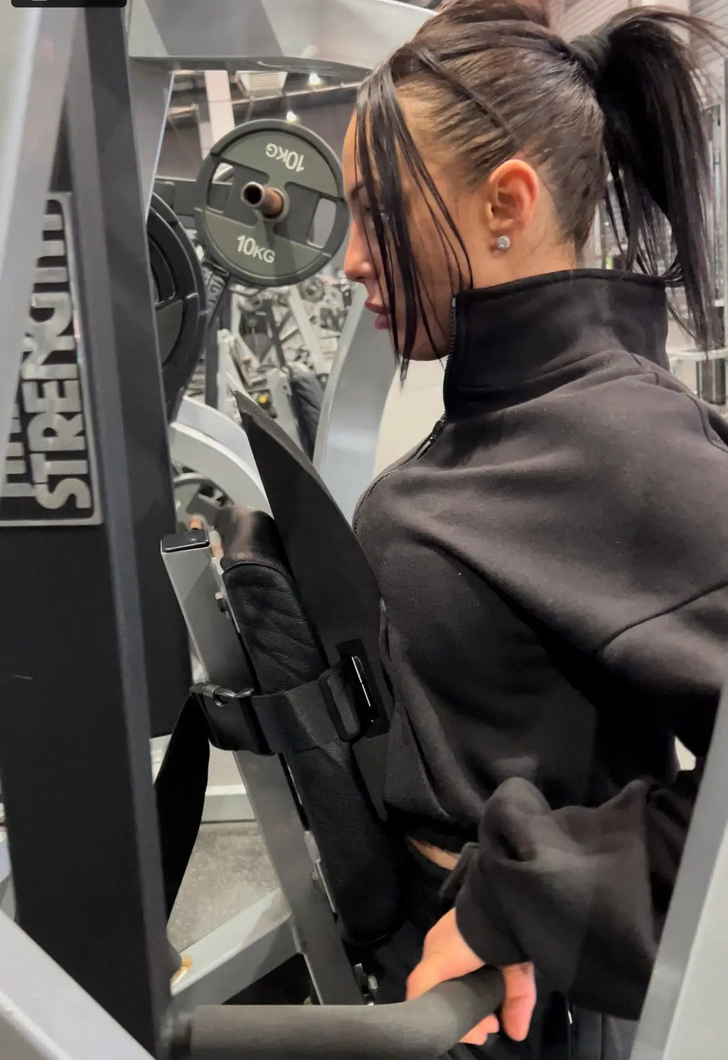 Cherneka 'Sug Kneez' Johnson using the EZBack Pro Level 1 strap on a row machine to support natural spinal curvature during back training.